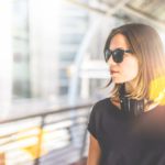 Chica con gafas de sol en una estación de tren con un corte de pelo para cara redonda media melena