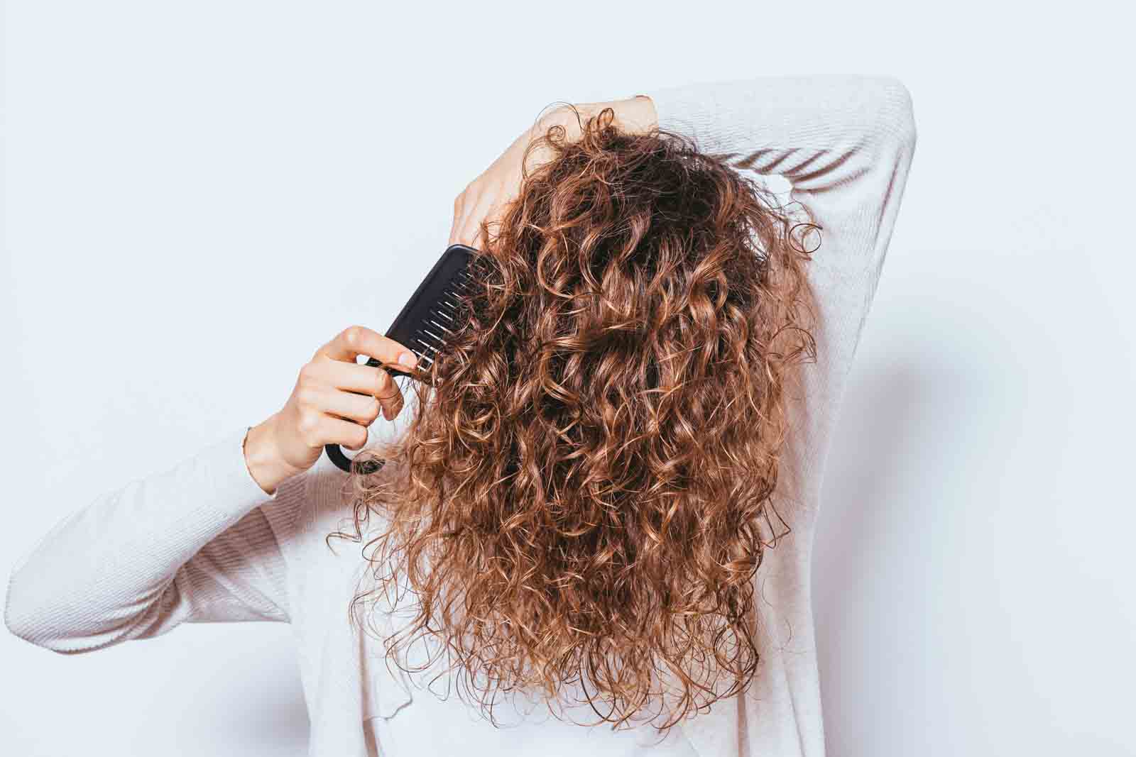 Mujer cepillando pelo con peine de púas anchas para pelo rizado