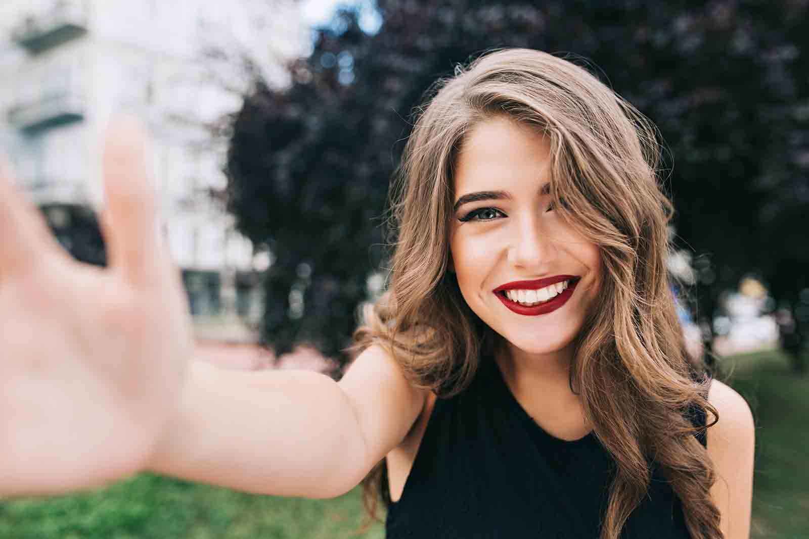 Selfie chica sonriendo con cabello castaño y sano 